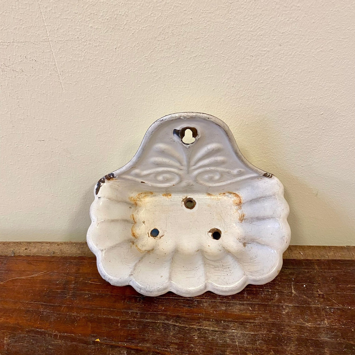 Soap dish seen from above with three drain holes and rust marks in the dish