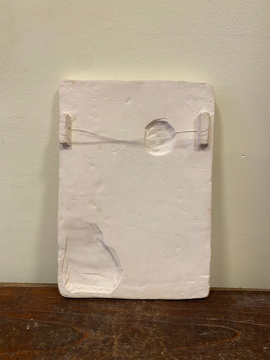 Back of the plaster relief with two small hanging tabs and a string