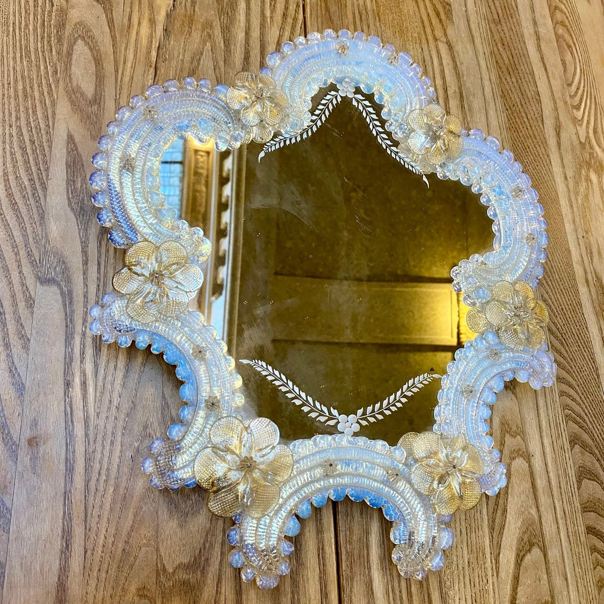 Close view of the glass flowers and beaded frame of a vintage Venetian mirror