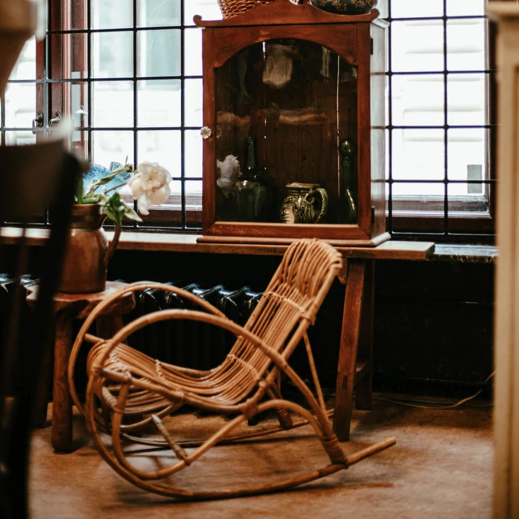 an old swing chair and a big wooden cabinet with glass door places in front of a large window.