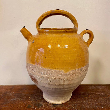 Terracotta jug with yellow glaze seen from the other side, with the spout on the left
