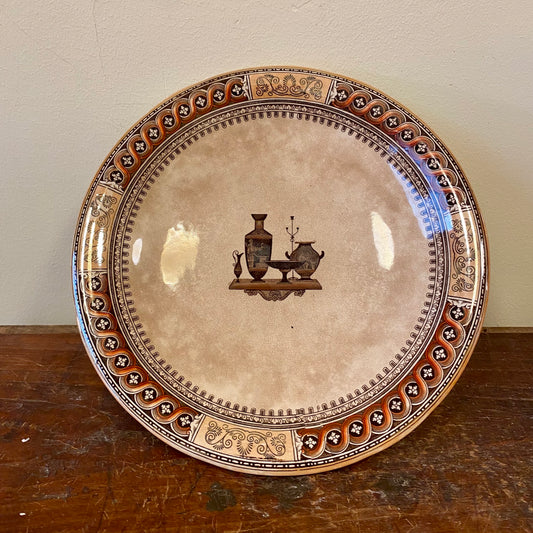 Antique English pedestal dish with a brown transfer print of Greek vases on a shelf and a rope-twist border, seen from above