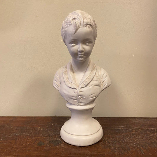Vintage bust of a young boy with short tousled hair and a buttoned jacket, on a round base, front view