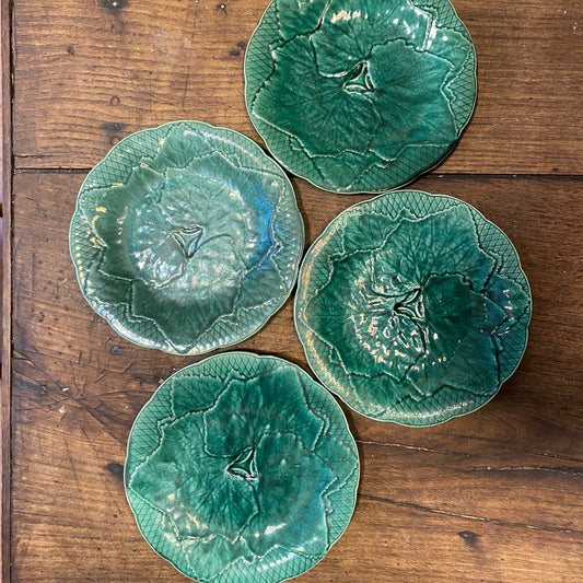 Four vintage Gien leaf plates in slightly different shades of green, seen from above on a wooden table