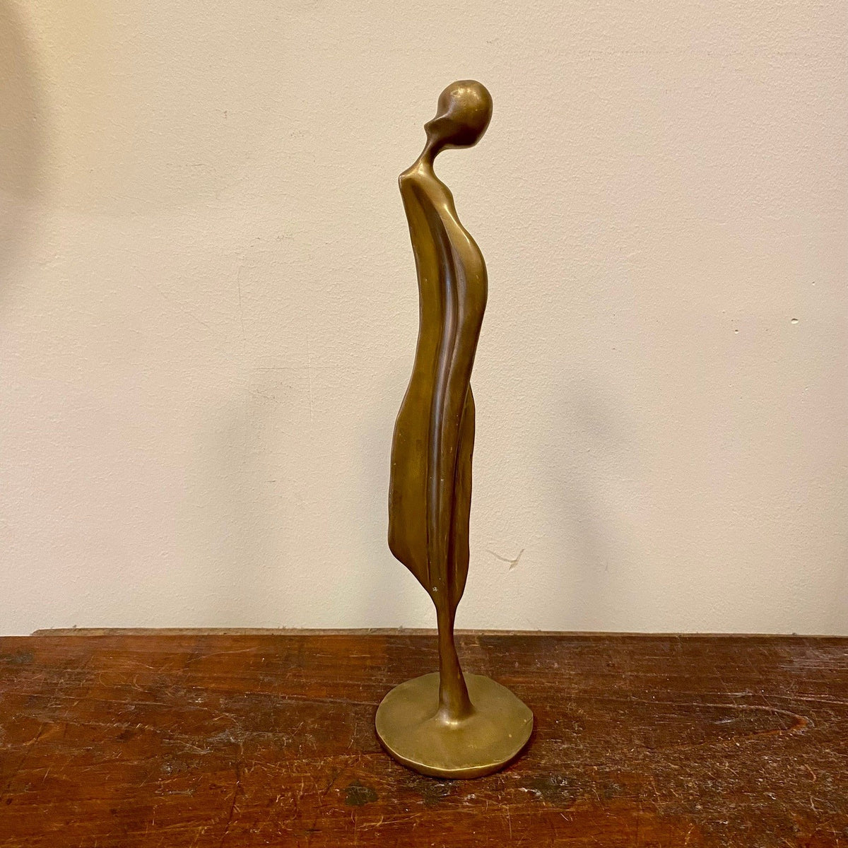 Abstrakt figur i mässing på rund bas, sidovy