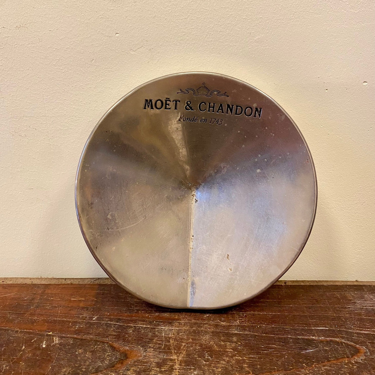 Vintage Moët & Chandon-reklamaskfat med polerad silverfärgad yta och namn och krona i svart, framifrån