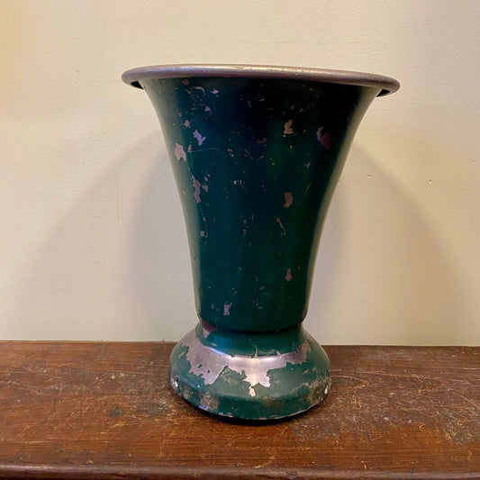 Vintage French florist vase in dark green painted metal, side view with worn paint showing bare metal on the base and body