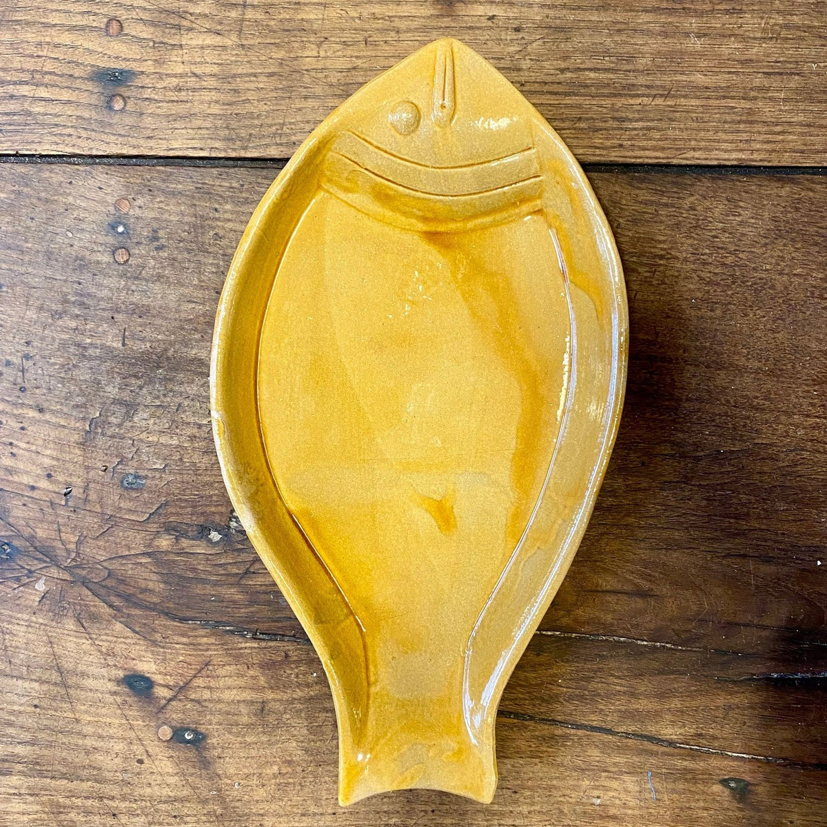 Yellow glazed fish-shaped serving dish with moulded eye and gill lines, seen from above