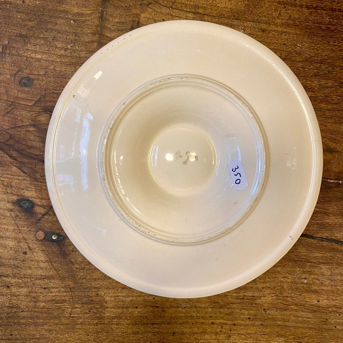 Underside of a vintage French off-white oyster plate with a round foot