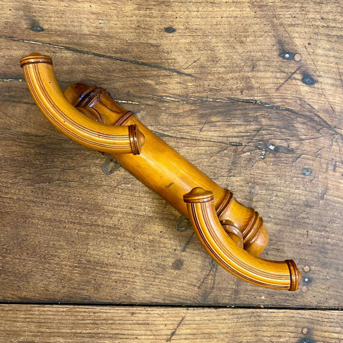Vintage French double wall hook seen from the side, showing the two curved hooks and the turned rail