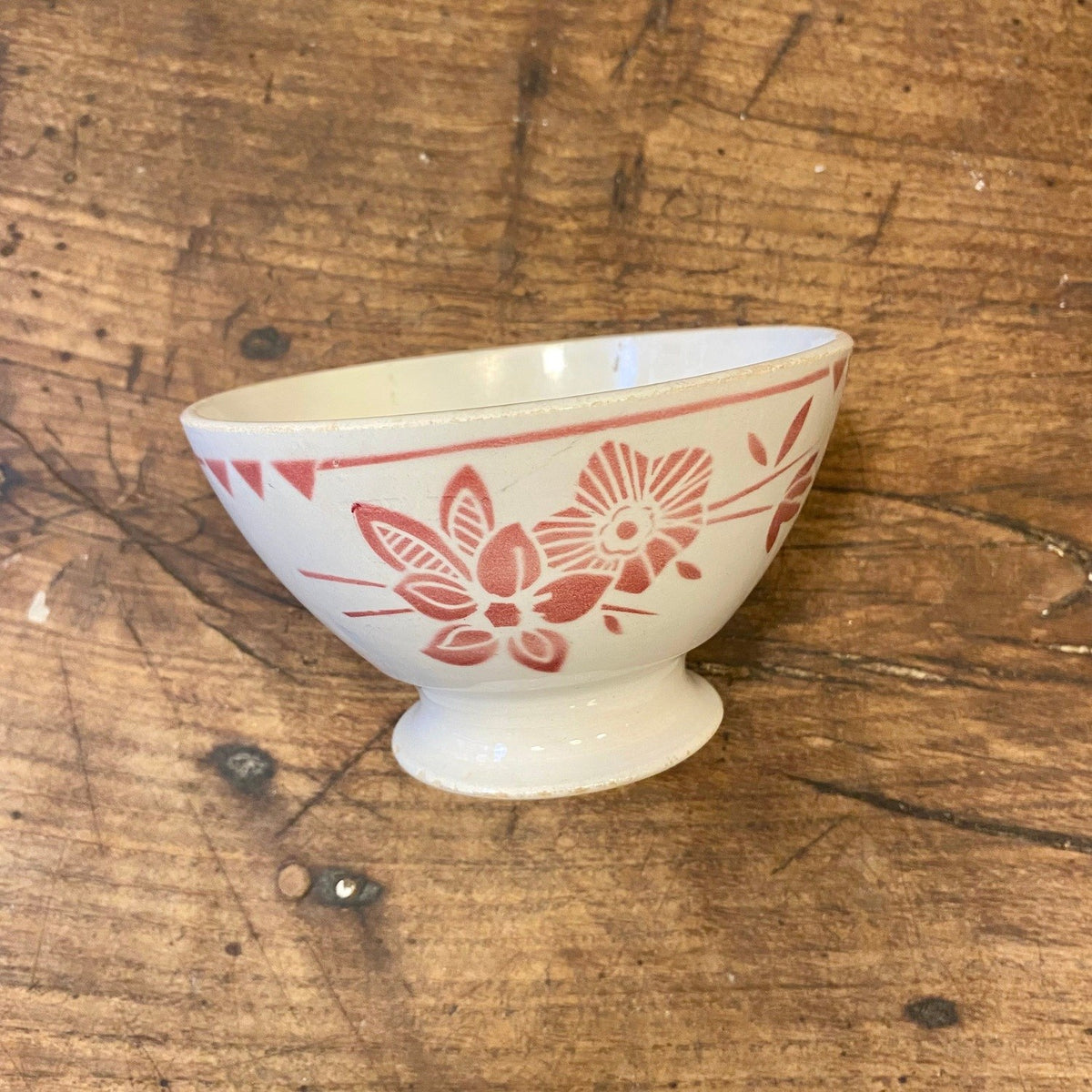 Vintage French café au lait bowl in off-white with pink flowers and a line and triangle pattern below the rim, on a footed base