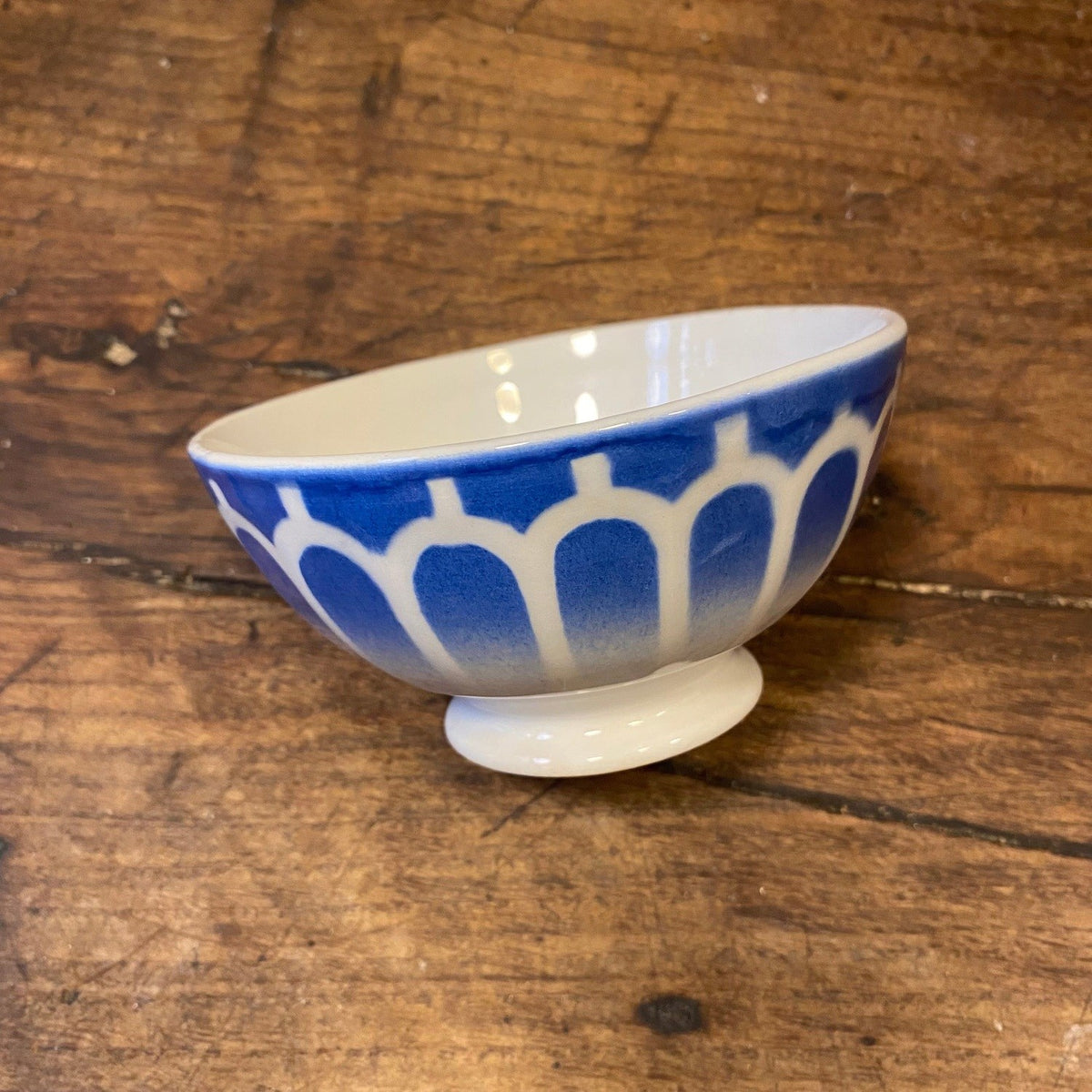Vintage French café au lait bowl in blue with a pattern of white arches, on a footed base