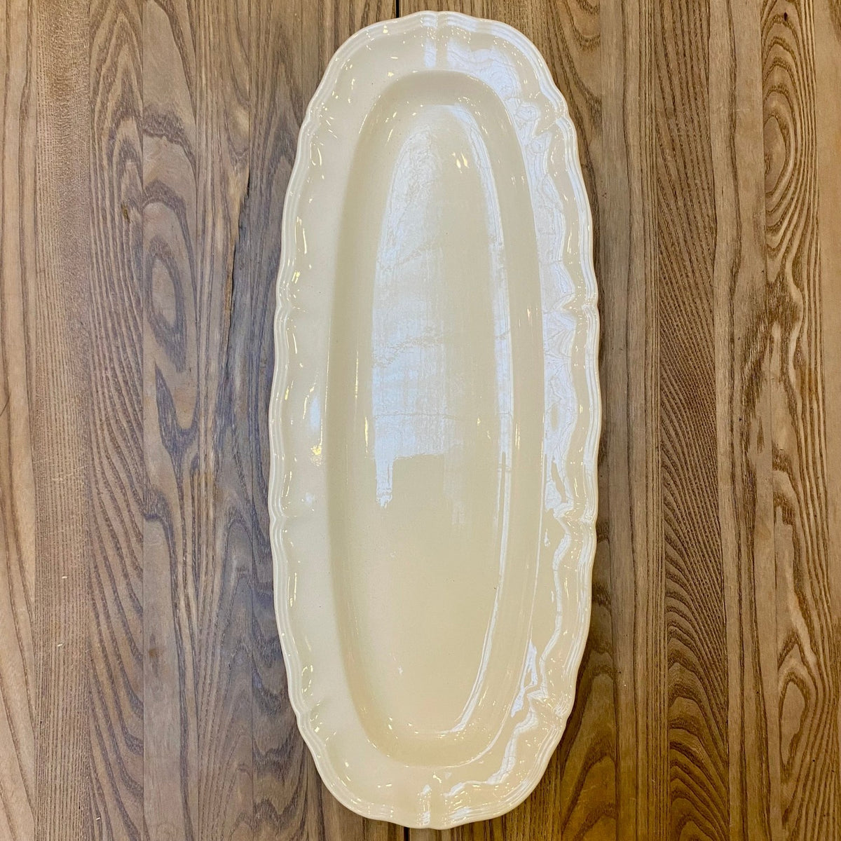Vintage French Sarreguemines serving platter, a long oval off-white dish with a scalloped rim, seen from above
