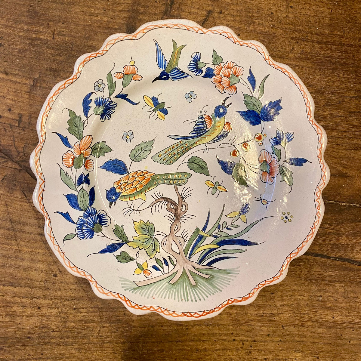 Vintage fransk väggtallrik med två handmålade fåglar bland blommor och insekter och en vågig kant med röd rutmönstrad bård