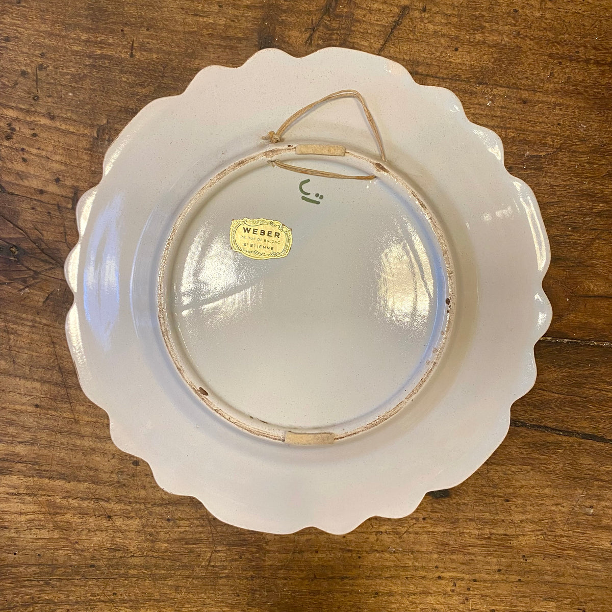 Baksidan av en vintage fransk väggtallrik med en Weber St Étienne-etikett och ett upphängningssnöre