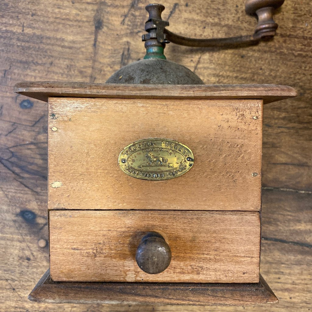 A wooden pepper mill with a vintage handle. Wooden background.