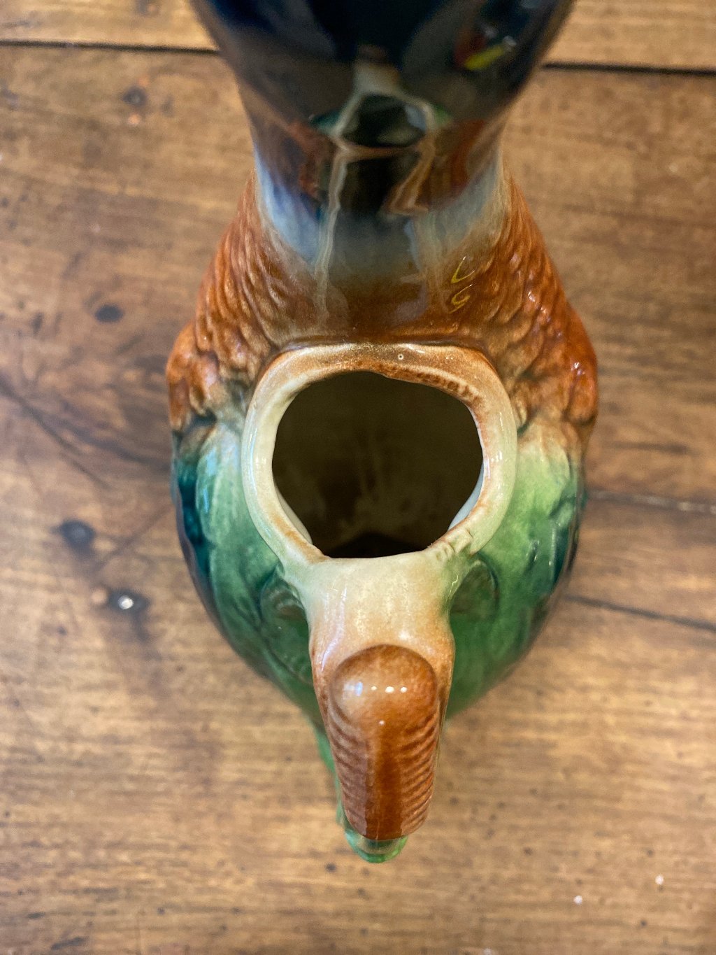 the top of a carafe shaped like a duck. Wooden background.