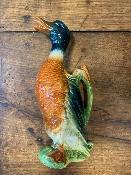 A carafe in the shape of a standing duck. Wooden background.