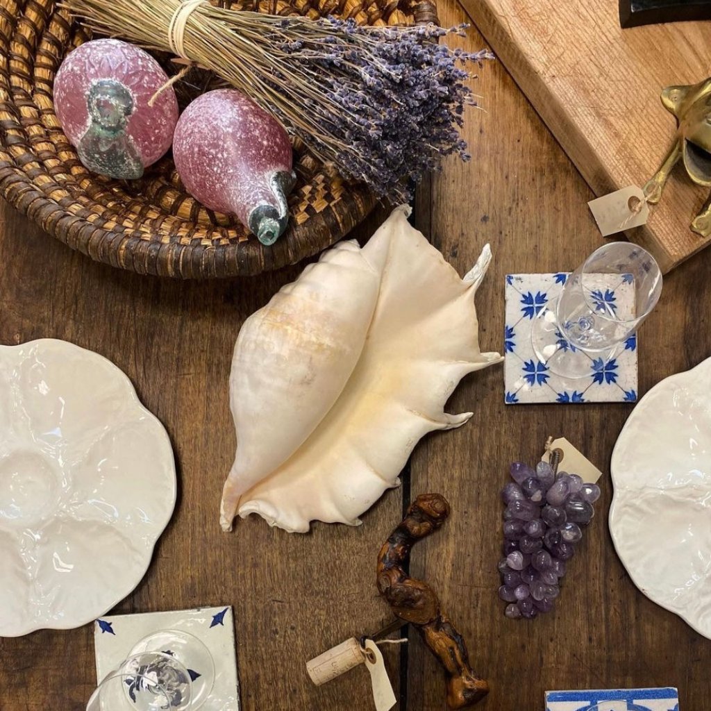 Decorative table setting with lavender, glass grapes, ceramic plates, and a large seashell centerpiece.