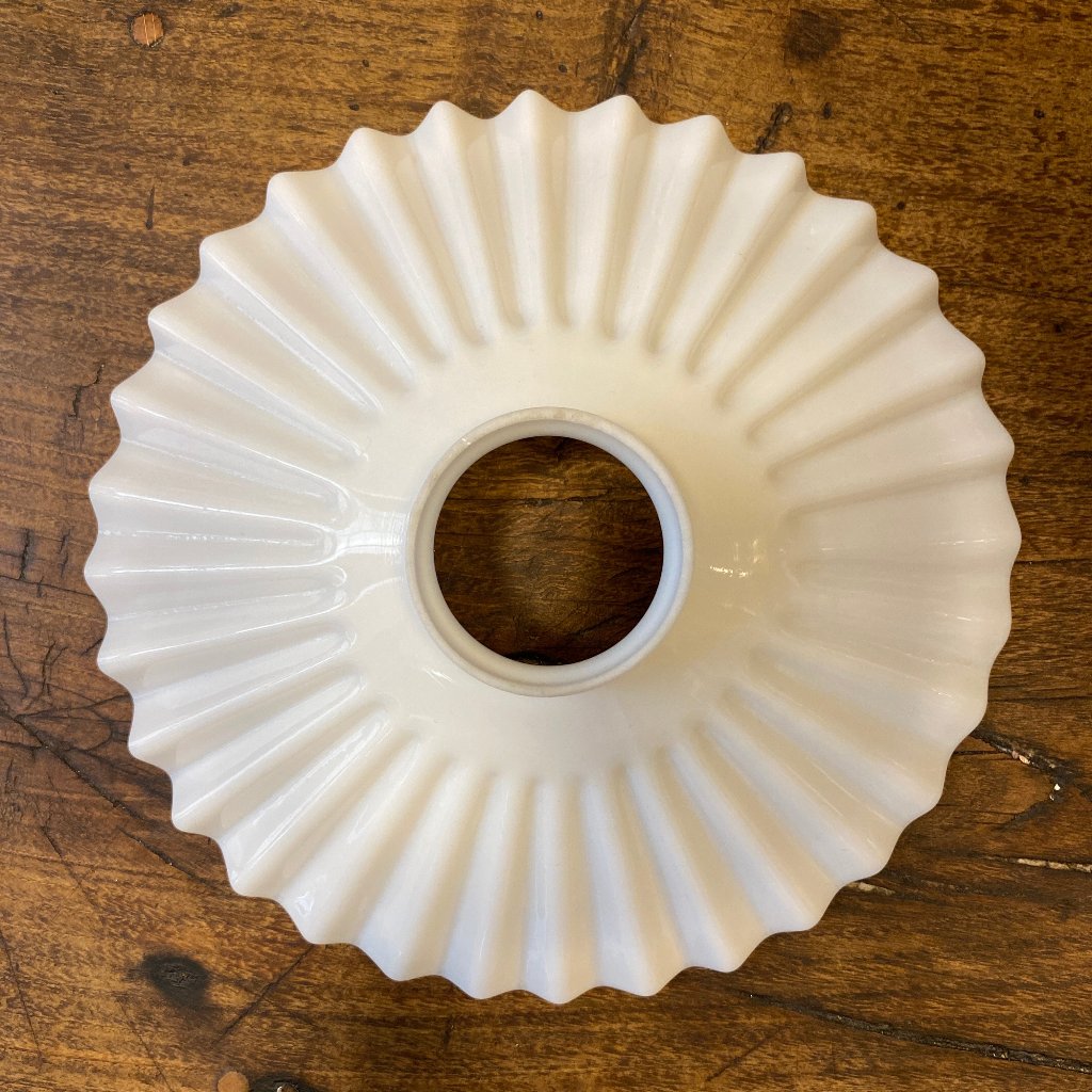 A white lamp shade in porcelain with a wavy design.