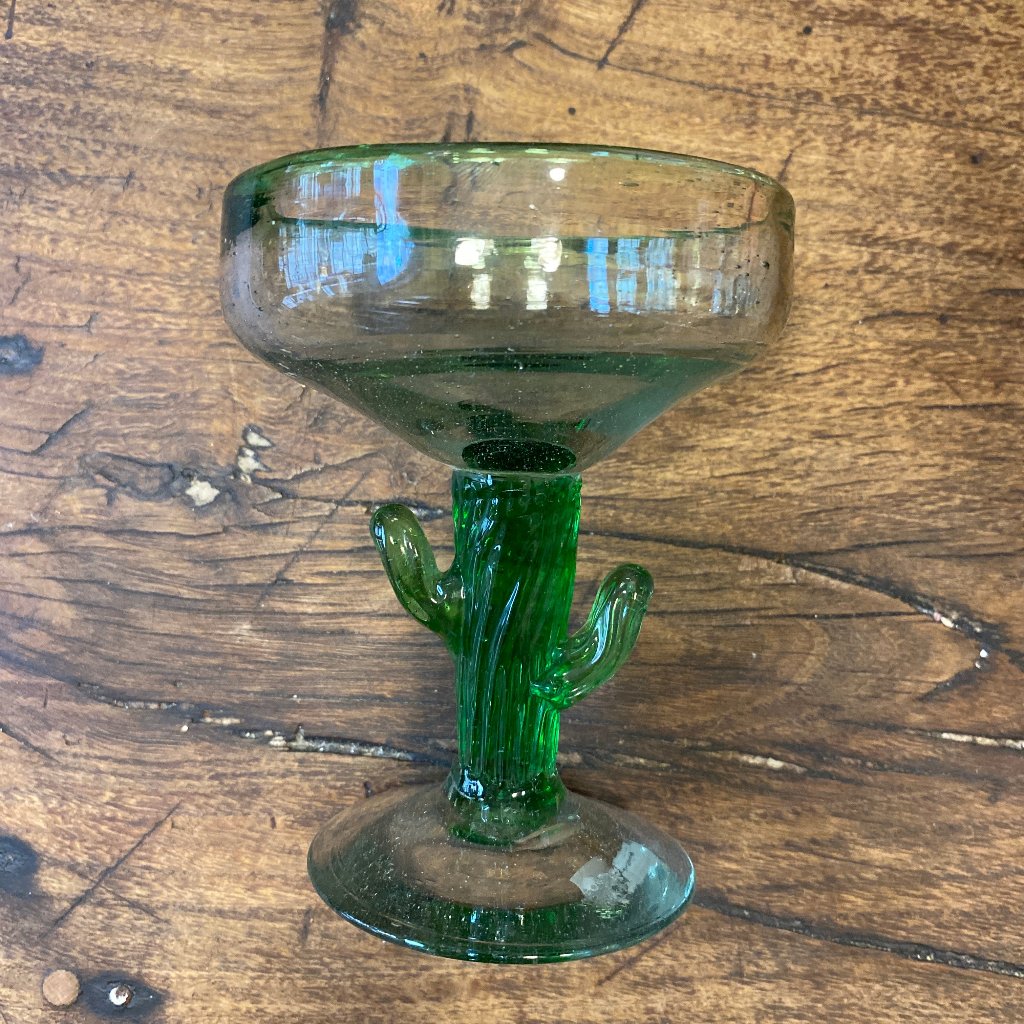 A margarita glass shaped like a cactus in the stem. Wooden backgorund.