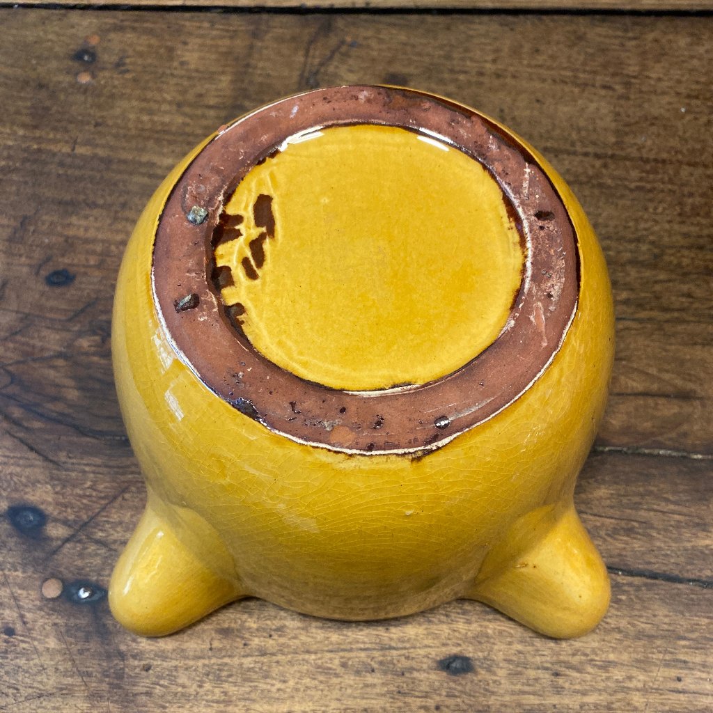 A yellow mortar from below. Wooden background.