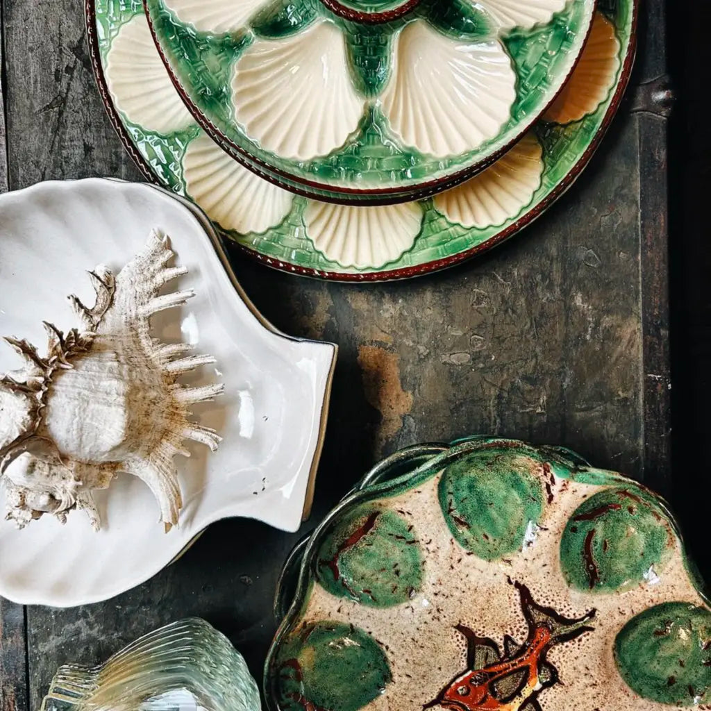 Vintage ceramic plates with shell and fish designs, displayed on a rustic wooden surface.