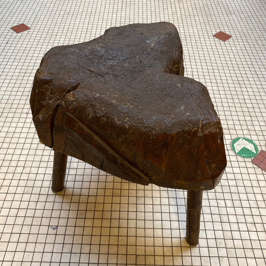 Dark wooden stool. Shaped like a tree trunk. 